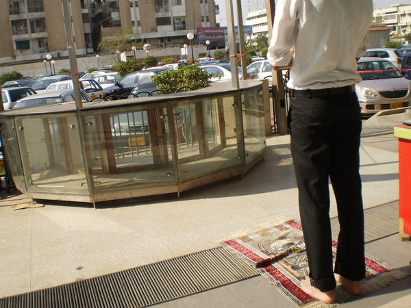 Sadaf: Young man offering dhuhr salah outside a shopping mall. The whole world is a prayer place for Muslims.